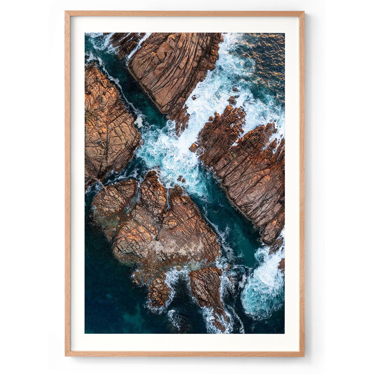 Vertical aerial photo of Canal Rocks in Western Australia near Yallingup. The deep blue ocean is crashing against the rocks creating whitewash that swirls around them. There is a tiny bridge leading from one rock to another on the left hand side. Original fine art photography, available as prints and framed wall art. Perfect for your living room, dining room, bedroom or home office. Shipped free worldwide.
