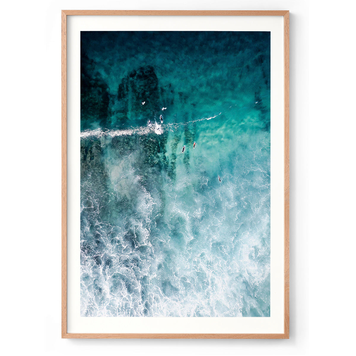 Vertical aerial photo of surfers in the ocean at Yallingup beach, Western Australia. The whitewash is coming in through the bottom of the photo and surfers are heading towards the top in the turquoise water. Perfect for a coastal home or beach house. Original fine art photography, available as prints and framed wall art.