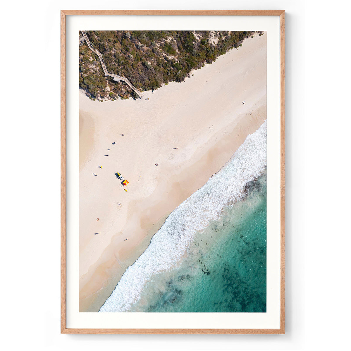 Vertical drone photo of Smiths Beach in Western Australia. The staircase comes down from the top left hand corner, there is an iconic red and yellow lifeguard tent and small surfers dot the white sand as they walk in a line towards the stairs. The turquoise blue water comes in the bottom right hand corner. Perfect for the modern beach home or coastal interior. Original fine art photography, available as prints and framed wall art.