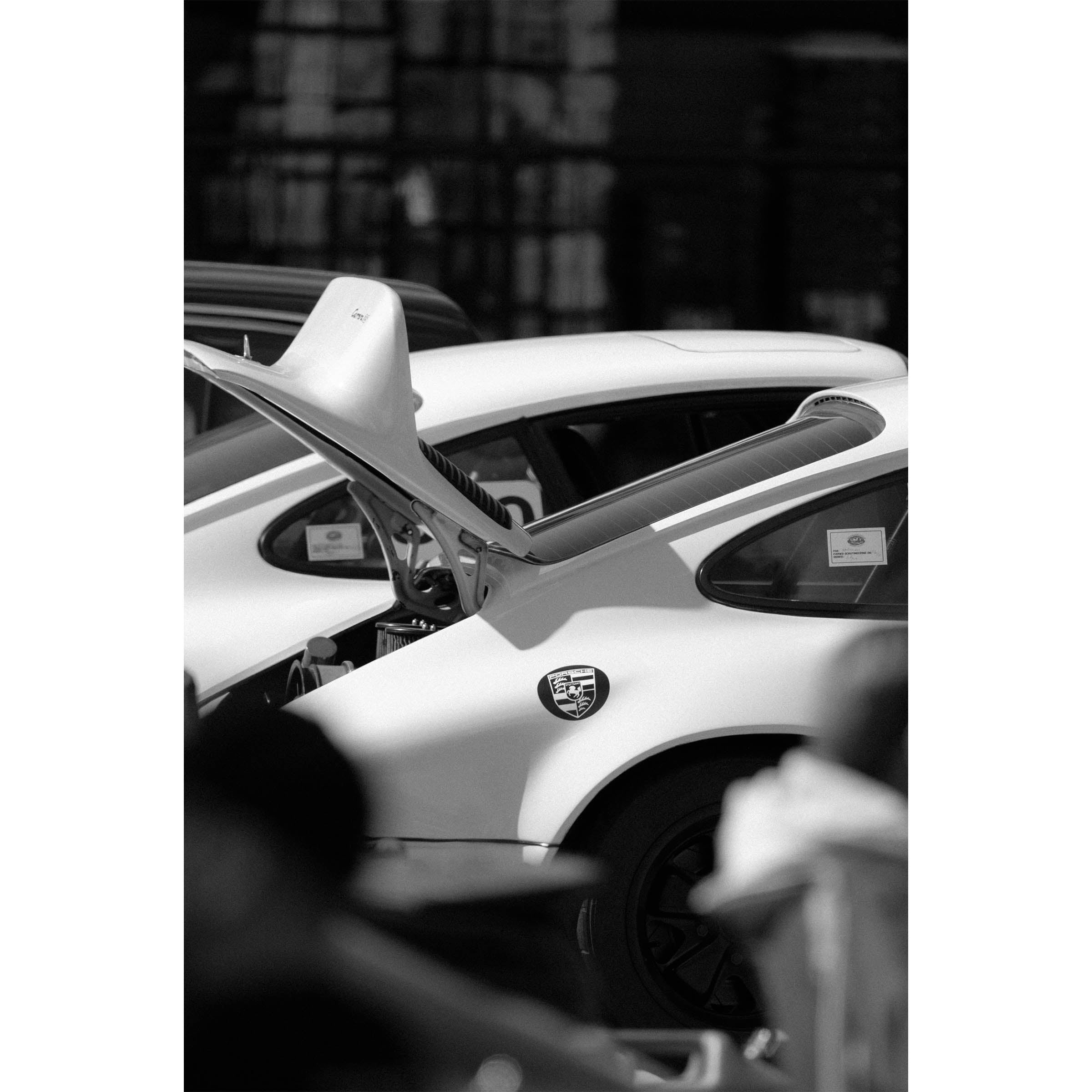 Black and white framed photograph of a Porsche 911 with its boot open waiting to race again. Fine art photography prints, available framed in black, white or oak.