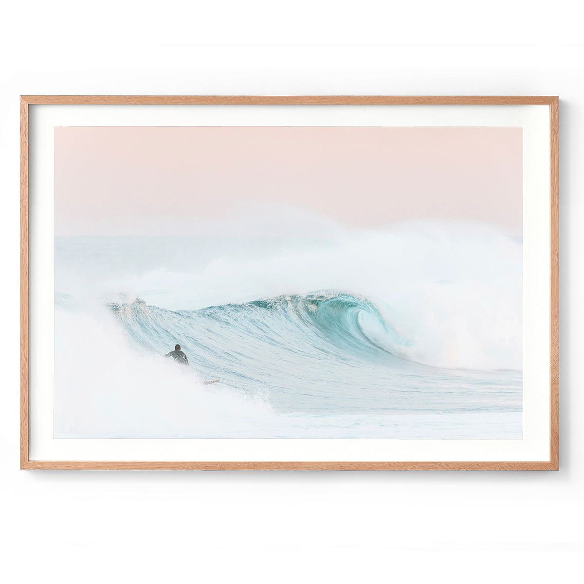 Framed photo of a surfer on a light blue wave with a pink sky at sunrise at Yallingup Beach in Western Australia. Available framed in oak, black or white.