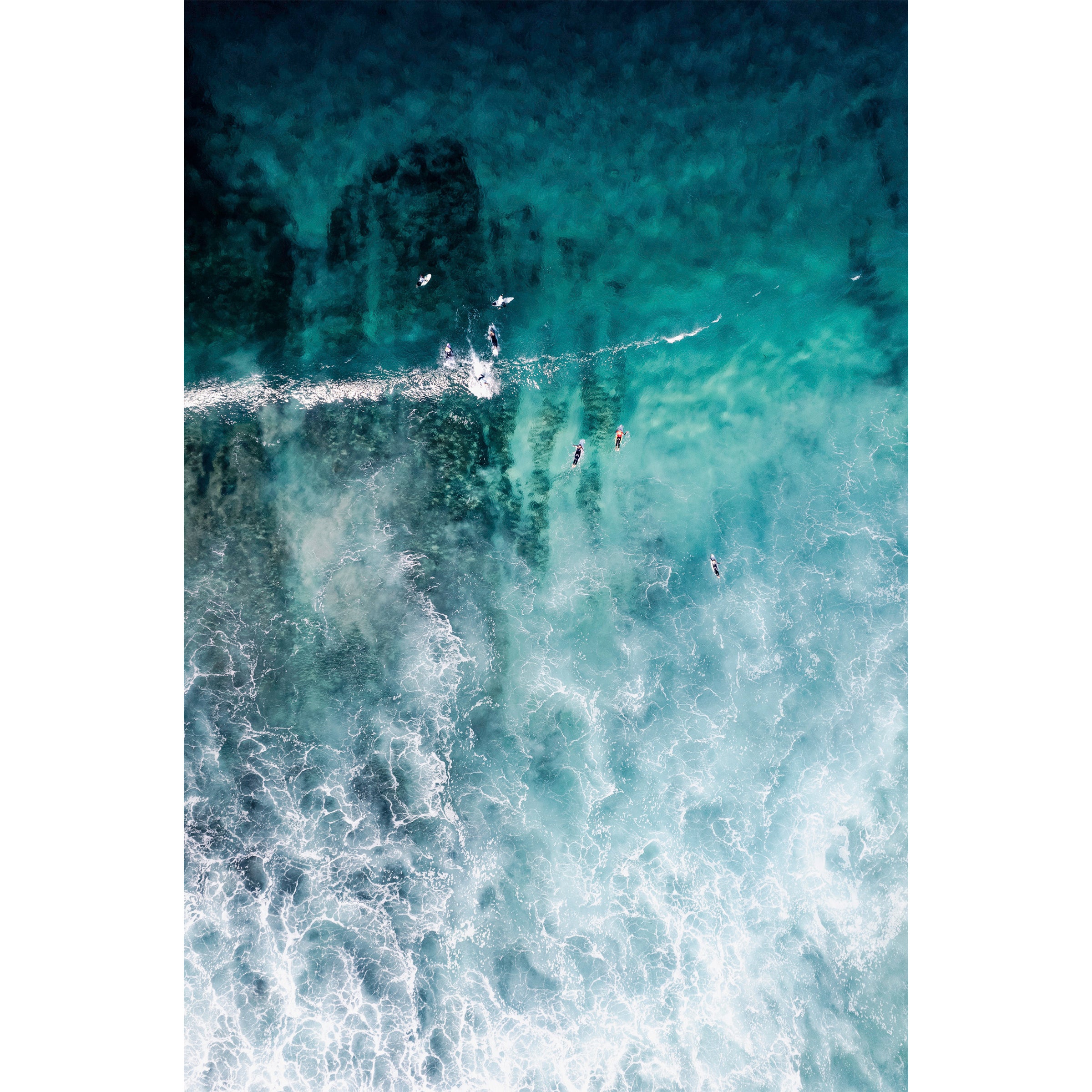 Vertical aerial photo of surfers in the ocean at Yallingup beach, Western Australia. The whitewash is coming in through the bottom of the photo and surfers are heading towards the top in the turquoise water. Perfect for a coastal home or beach house. Original fine art photography, available as prints and framed wall art.