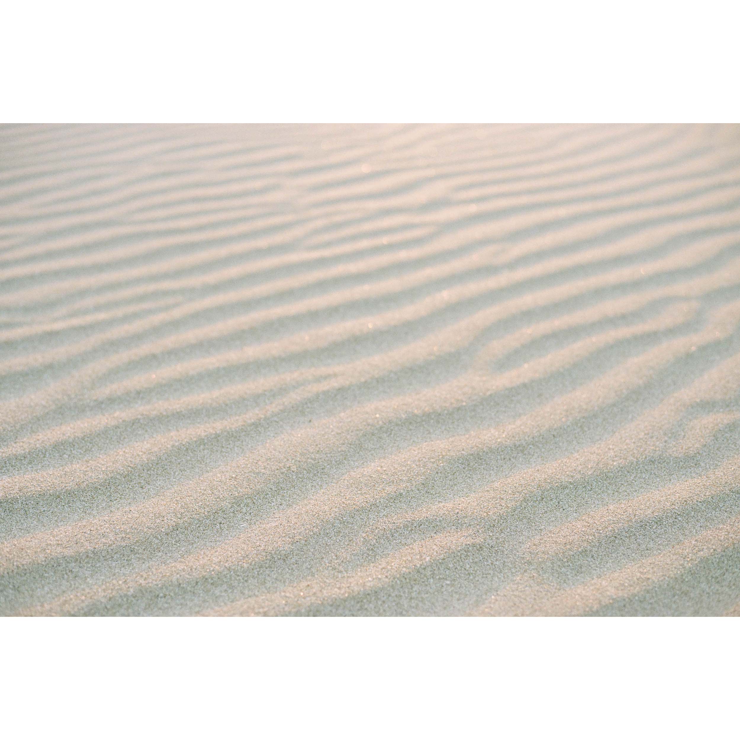 Horizontal close up photo of ripples of beach sand, with a golden glow from sunset. Perfect for the coastal home or beach house. Available as fine art photography prints and framed wall art.