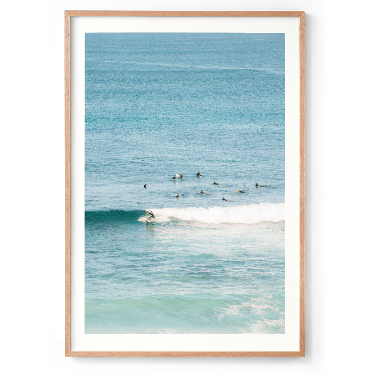 Colour photo of a surfer on a wave with others in the background waiting in the line-up. Shot at Injidup Beach in Yallingup, Western Australia. Fine art photography print, available framed in black, white and oak.