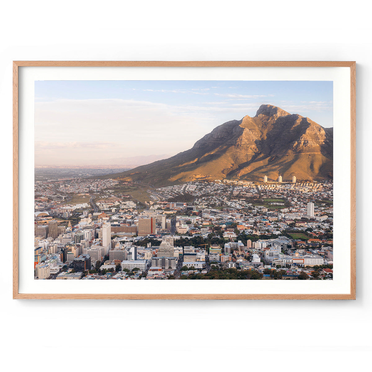 Framed photo of Table Mountain in Cape Town, South Africa. The city is in the foreground and the mountain is hit with golden light at sunset. Fine art photography prints, available framed in black, white or oak.