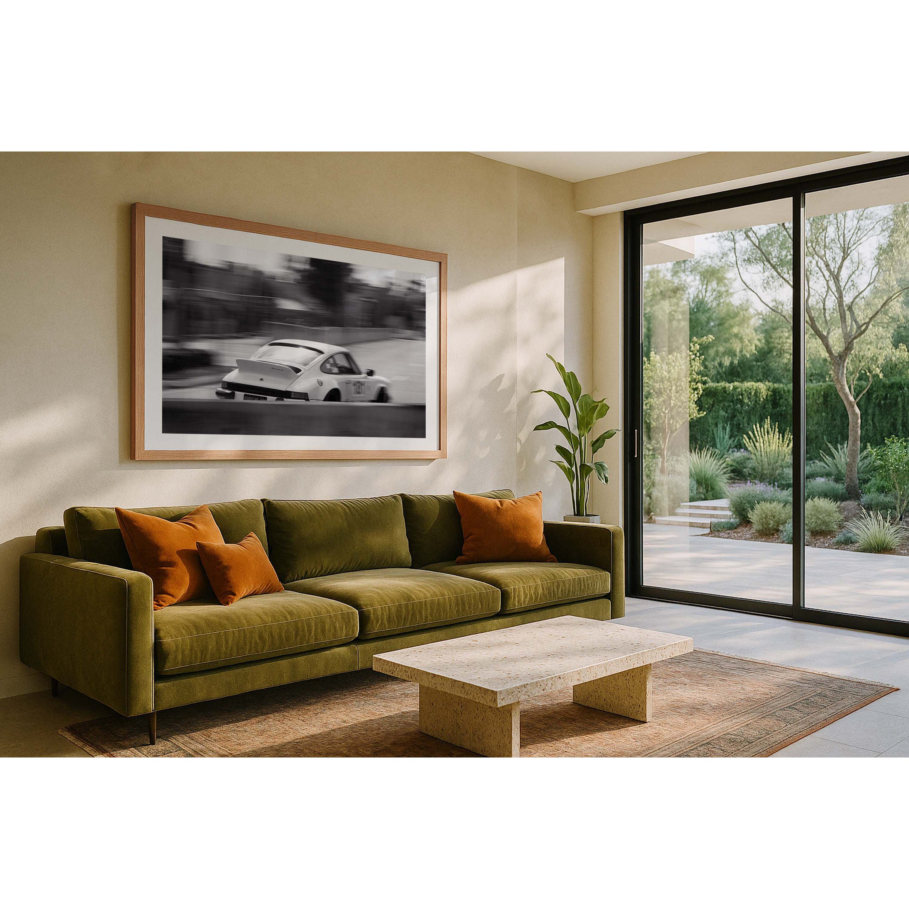 Horizontal black and white photo of a white Porsche 911 racing in the streets, the background is blurred as it goes around a corner. Pictured above an olive green couch in a house. Fine art photography prints, available framed in black, white or oak.