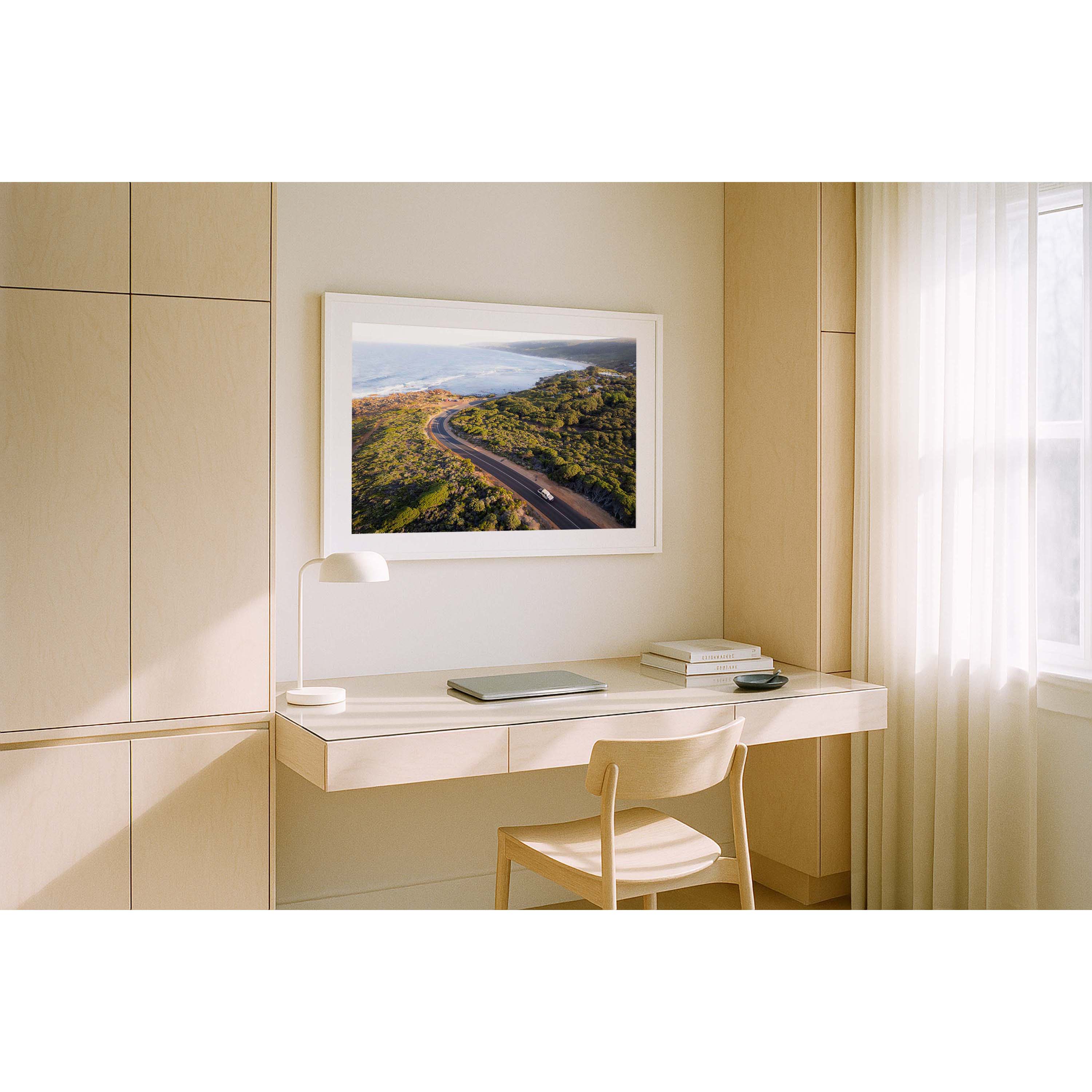 Horizontal photo of the road down to Yallingup beach in Western Australia. Taken from above at sunrise so it has a golden glow, with a car driving up the hill and the ocean in the background. Perfect for the coastal home or beach house. Available as fine art photography prints and framed wall art.