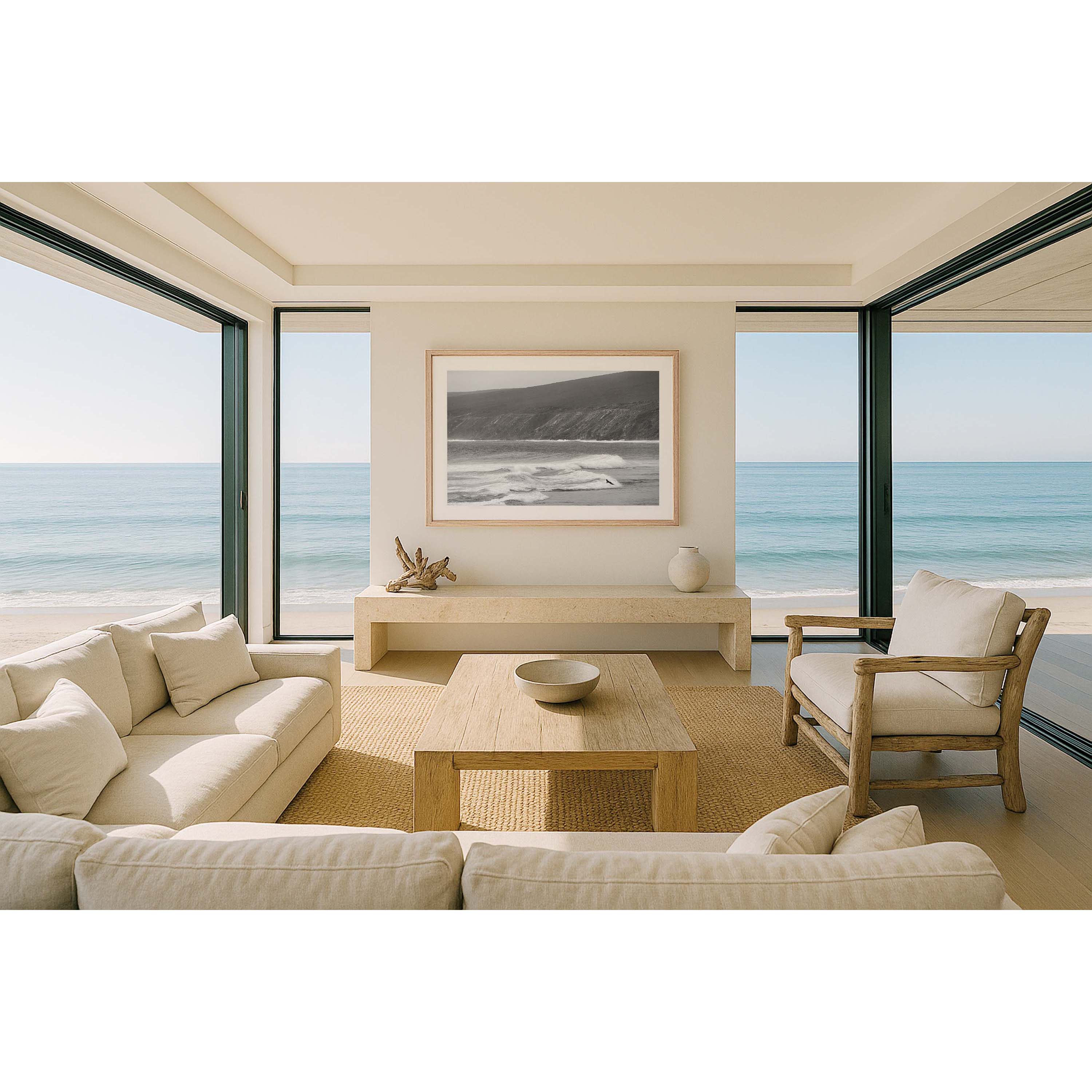 Horizontal black and white photo of a person mid air as he moves onto his surfboard in the ocean to paddle out at Yallingup Beach in Western Australia. The iconic cliffs of Rabbit Hill are in the background. It has a nostalgic feel. Fine art photography prints, available framed in black, white or oak.