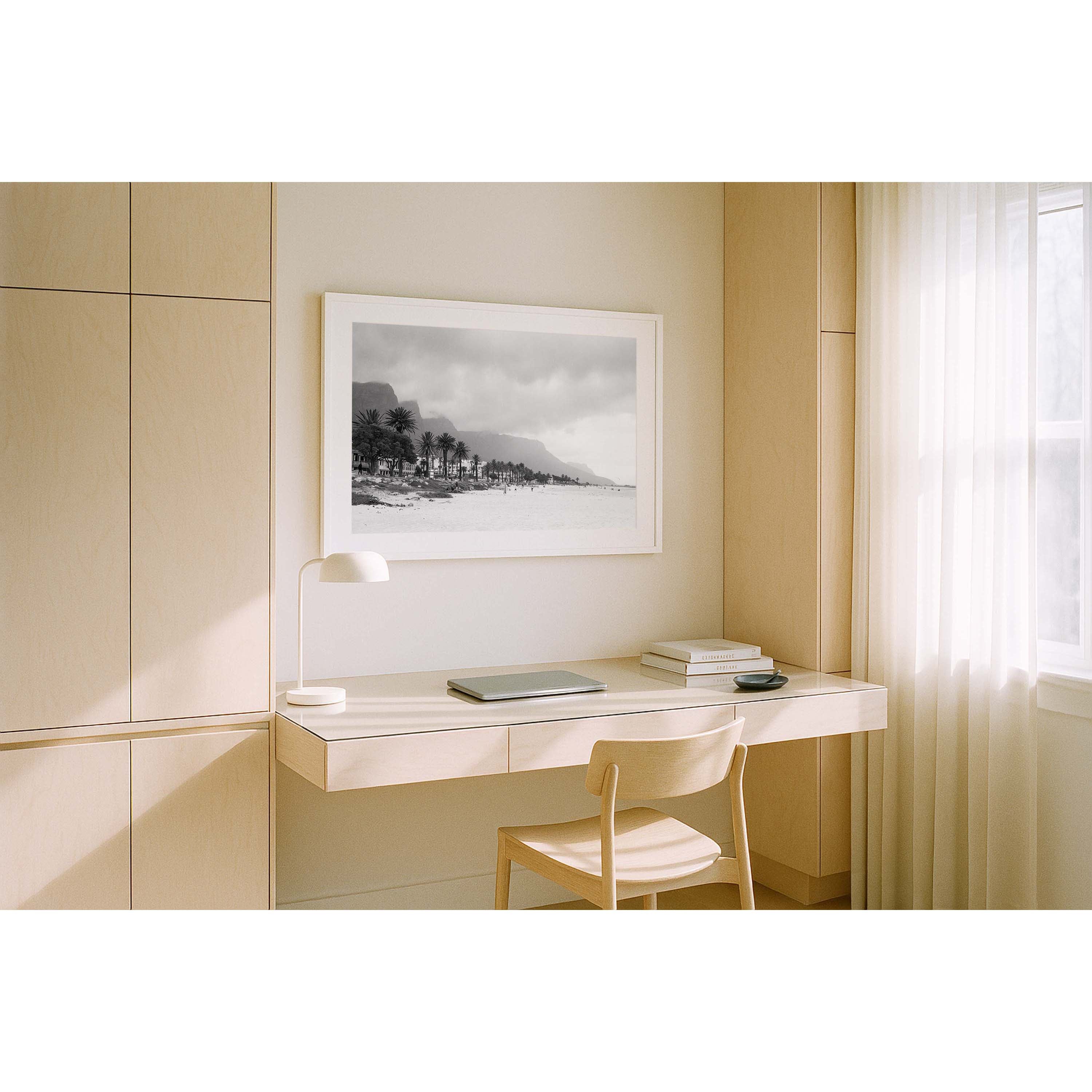 Horizontal black and white photo of Camps Bay Beach in Cape Town, South Africa. The palms line the edge of the sand and the mountains rise in the background behind clouds. Shot on film it has a moody, nostalgic feel. Fine art photography prints, available framed in black, white or oak.