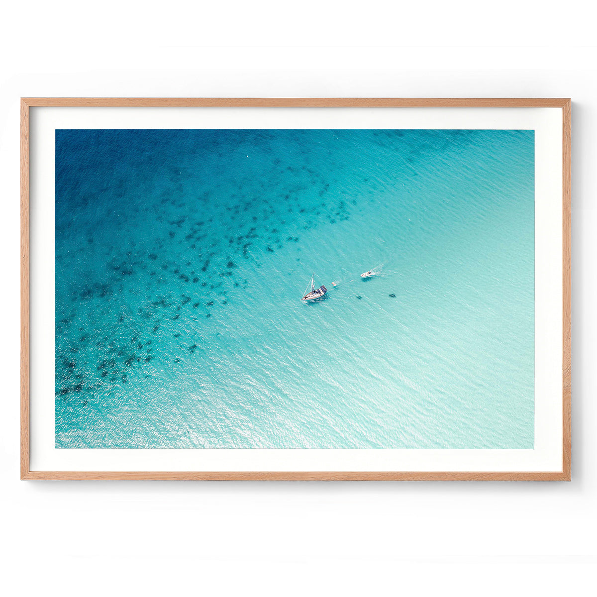 Horizontal drone photo taken at Eagle Bay in Western Australia, the ocean is blue and sparkling and there is a singular boat floating through the water. Minimalist fine art photography for coastal interiors and beach homes. Original framed wall art, exclusive to Host Studio. 