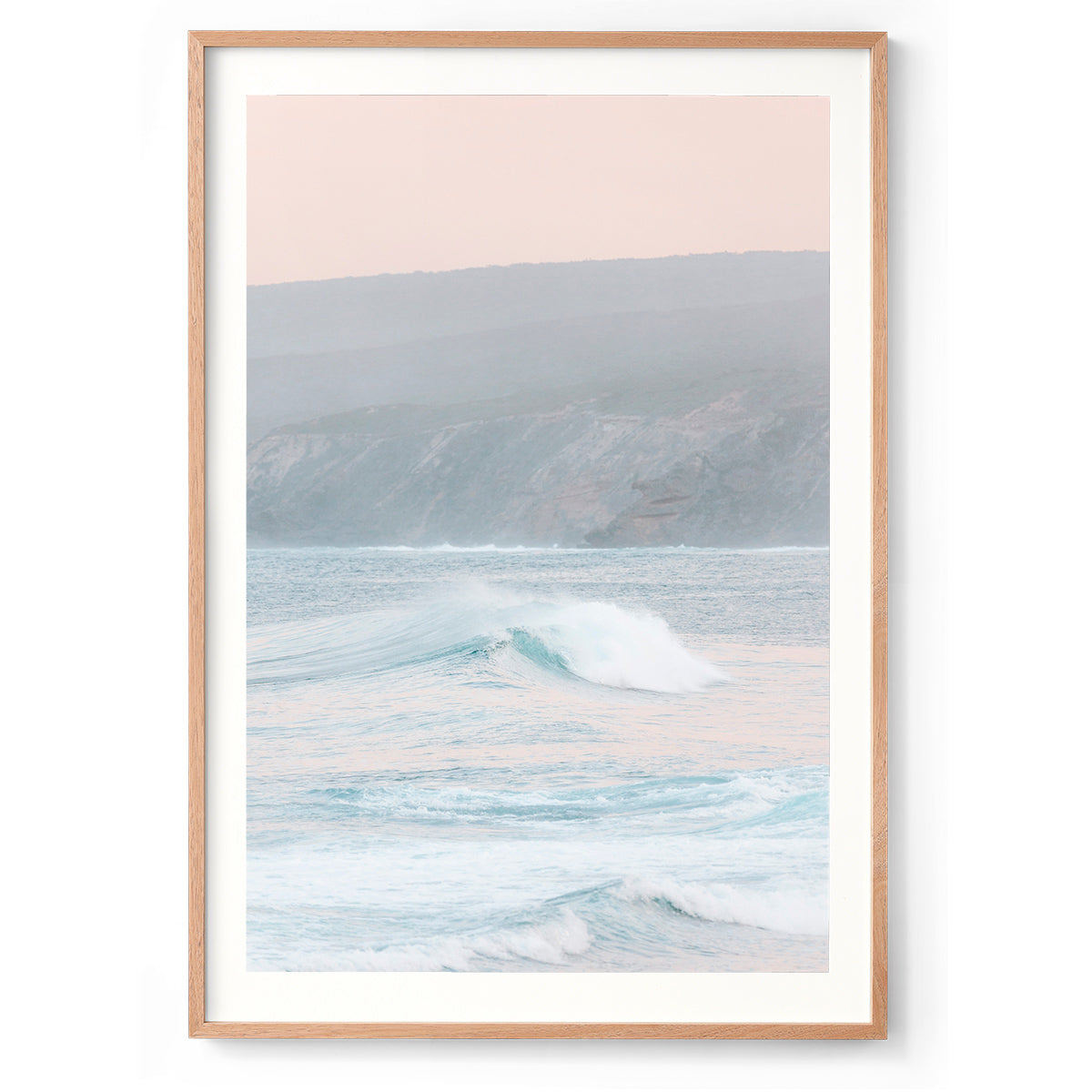 Vertical photo of a pastel sunrise over Yallingup Beach in Western Australia. The colours are soft with the waves rolling in and the cliffs in the background. Available framed in black, white and oak.