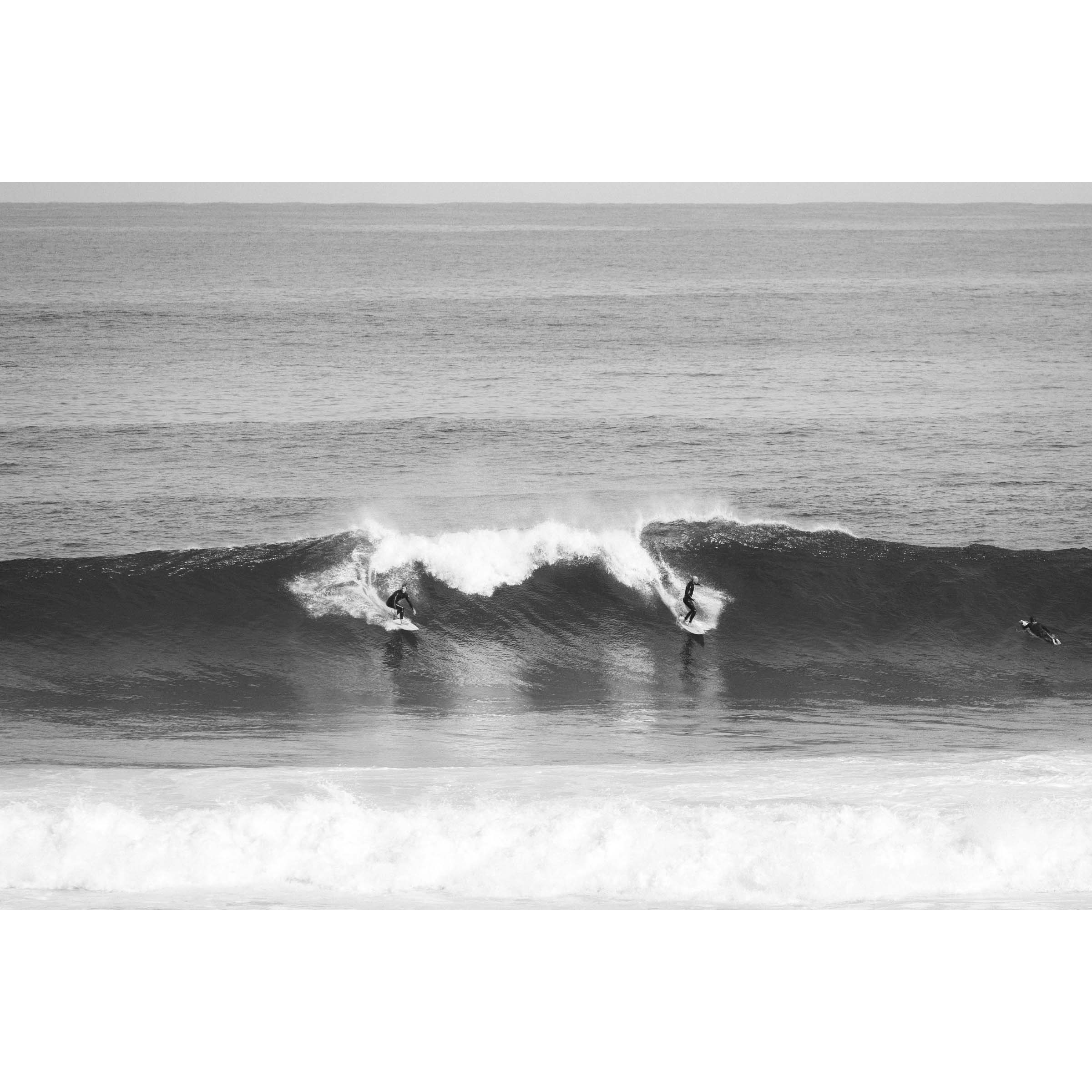 Black and white photo of two surfers riding a wave at Surfer's Point in Margaret River, Western Australia. Fine art photography prints, available framed in black, white or oak.