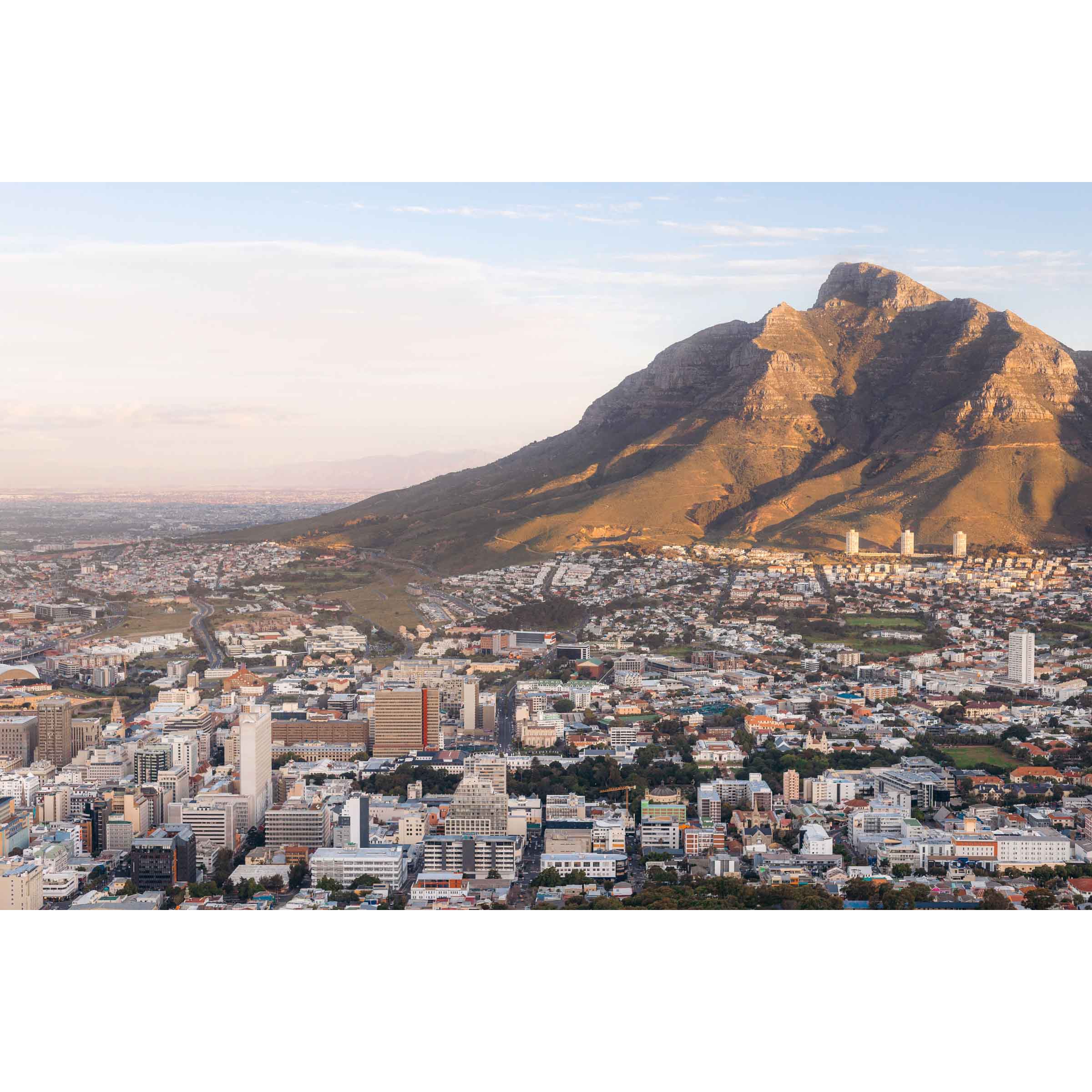 Framed photo of Table Mountain in Cape Town, South Africa. The city is in the foreground and the mountain is hit with golden light at sunset. Fine art photography prints, available framed in black, white or oak.