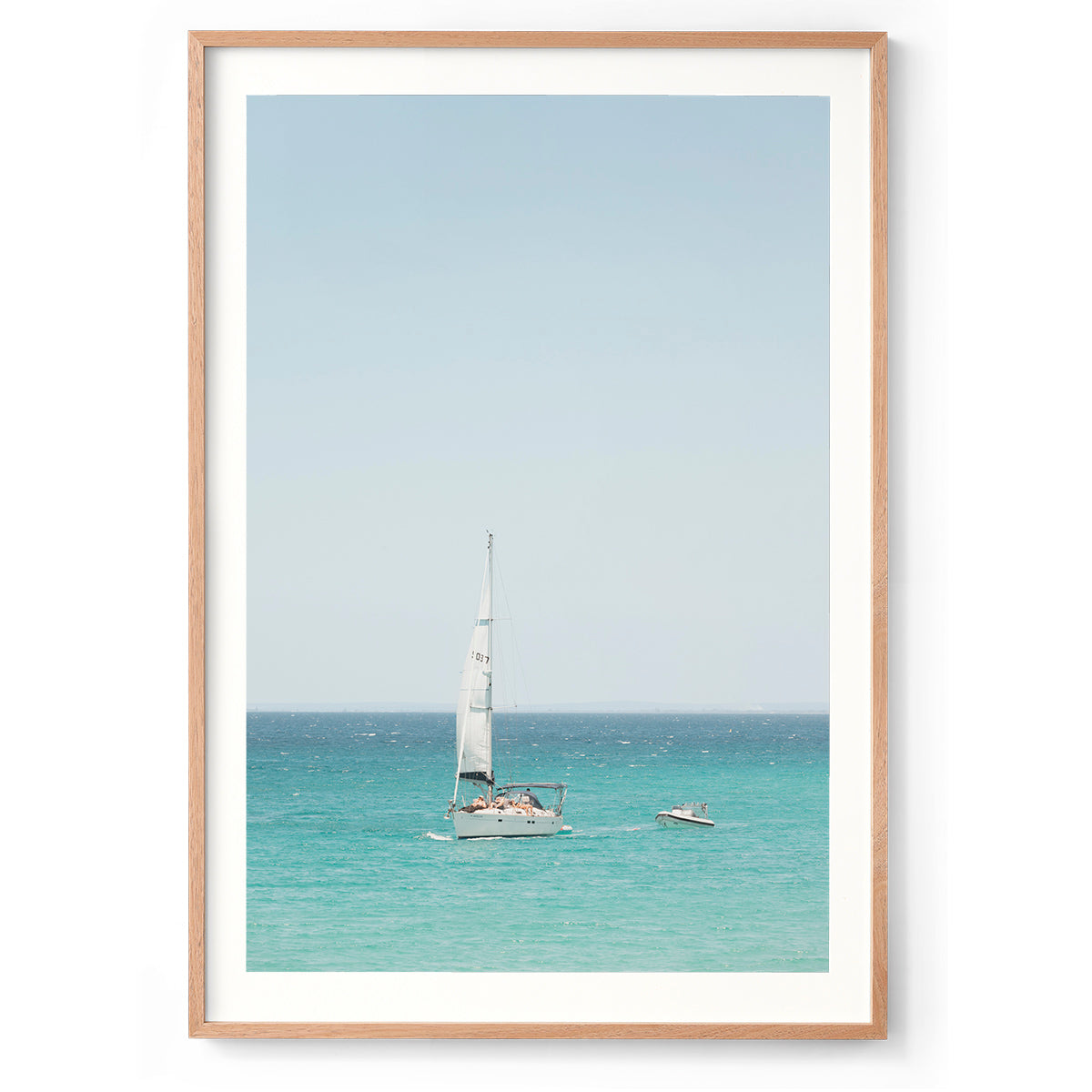 Colour photo of a sailboat on the water off Eagle Bay in Western Australia, tugging a smaller boat. There are people sunbathing on the deck. Fine art photography print, available framed in black, white or oak.