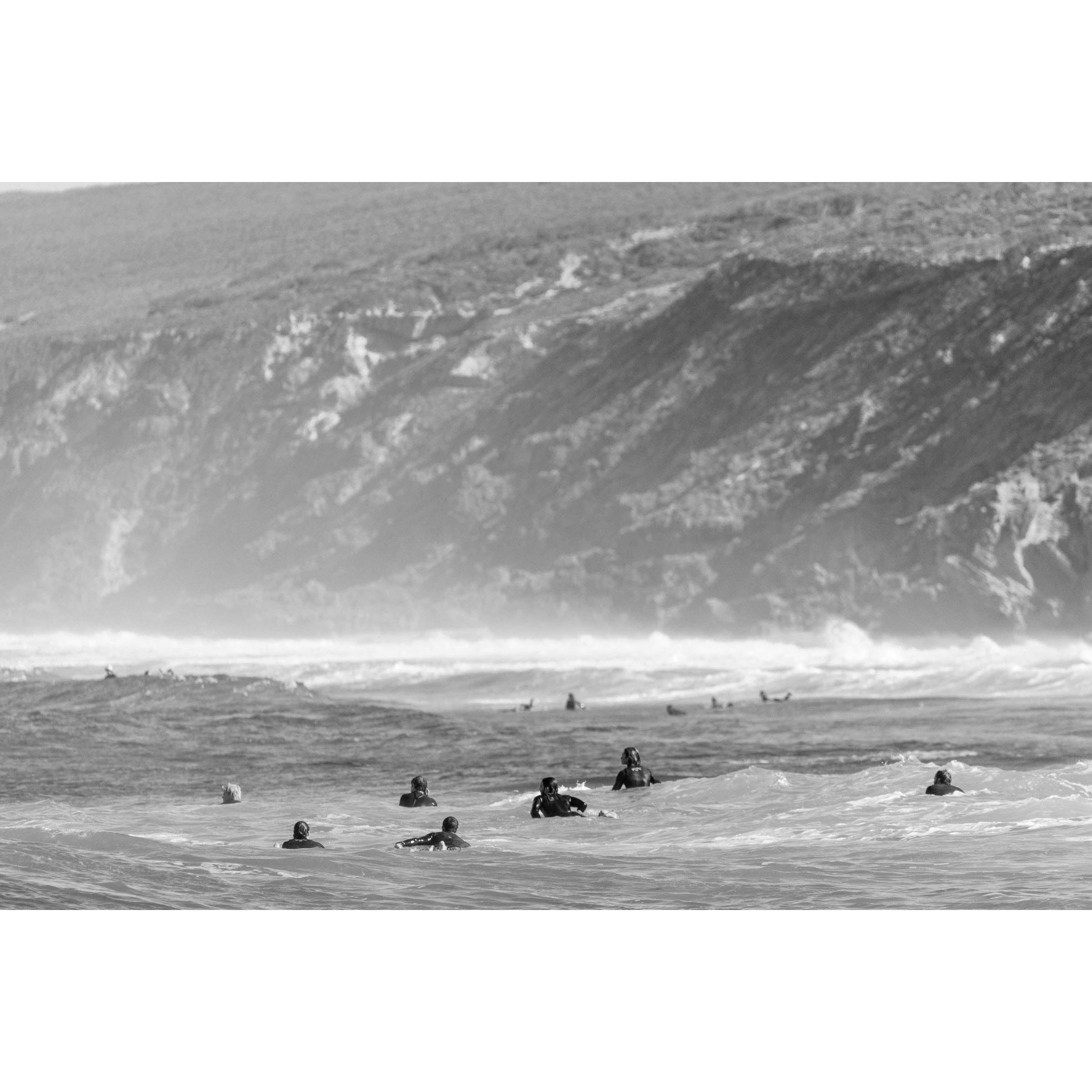 Black and white photo of surfers paddling in the ocean at Yallingup Beach with Rabbit Hill in the background. Fine art photography print from Western Australia's south west, available framed in black, white or oak.