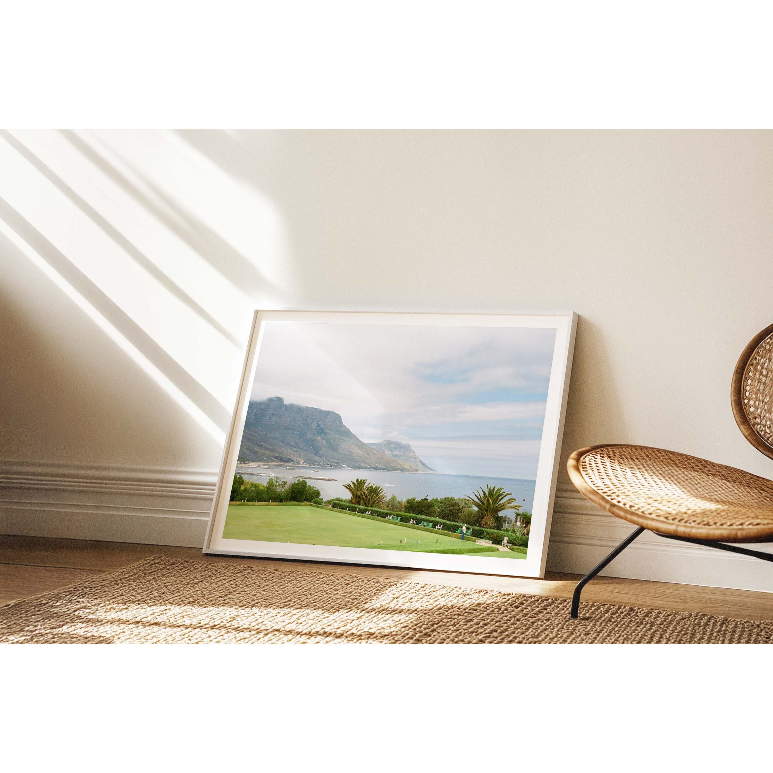 Horizontal framed photo of a bowling green overlooking the ocean in Cape Town, South Africa with the mountains in the background. Shot on film with soft colours. Fine art photography prints, available framed in oak, black or white.