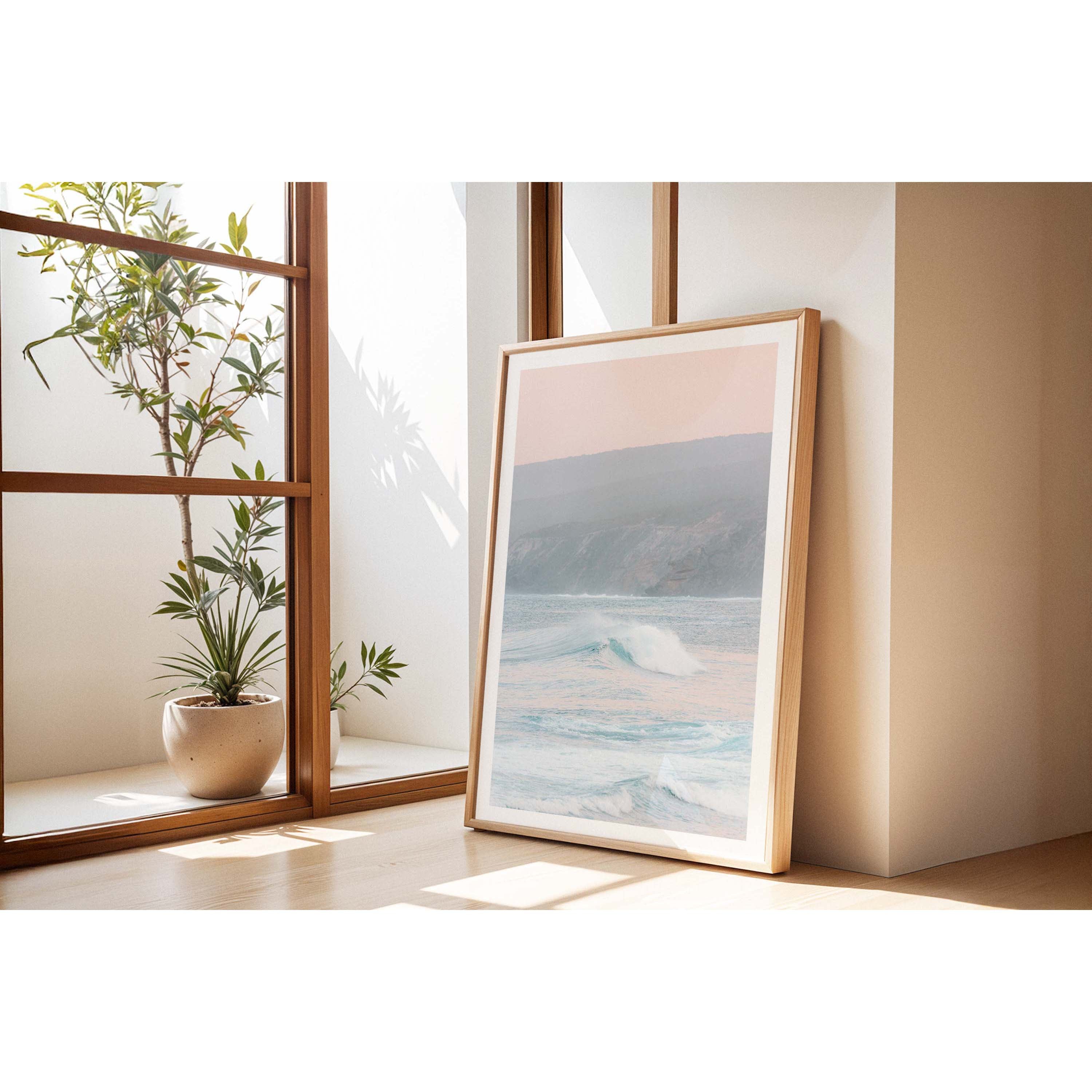 Vertical photo of a pastel sunrise over Yallingup Beach in Western Australia. The colours are soft with the waves rolling in and the cliffs in the background. Available framed in black, white and oak.