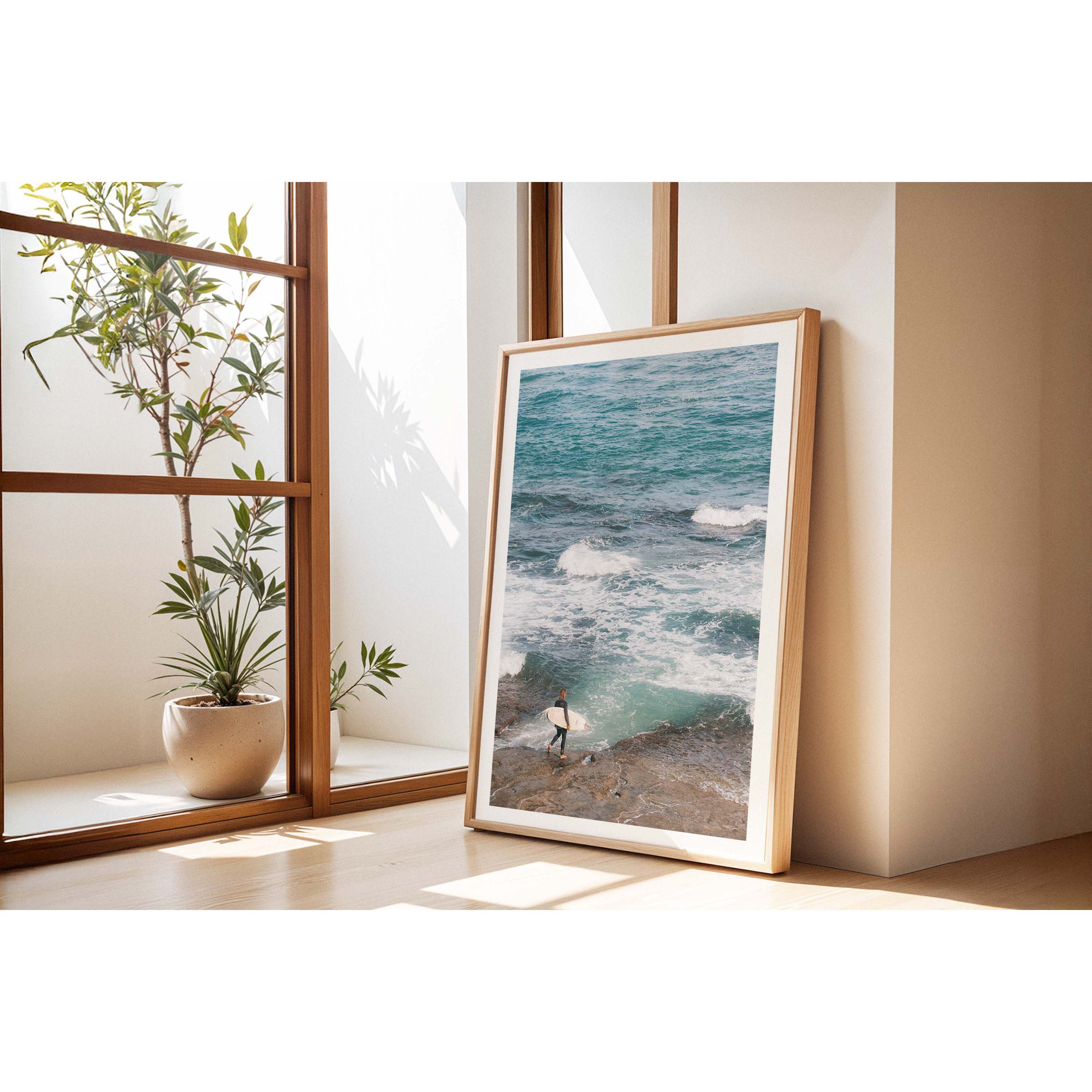 Person holding a surfboard on a rocky shore with ocean waves in the background. Shot at Surfer's Point in Margaret River, Western Australia. Available framed in black, white or oak.
